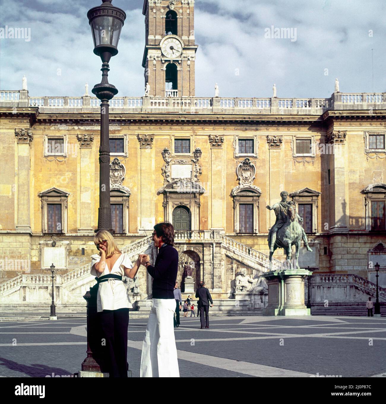 Vintage Rome 1970s, stylish couple flirting, Piazza del Campidoglio square, Palazzo Senatorio palace, Capitoline Hill, Italy, Europe, Stock Photo
