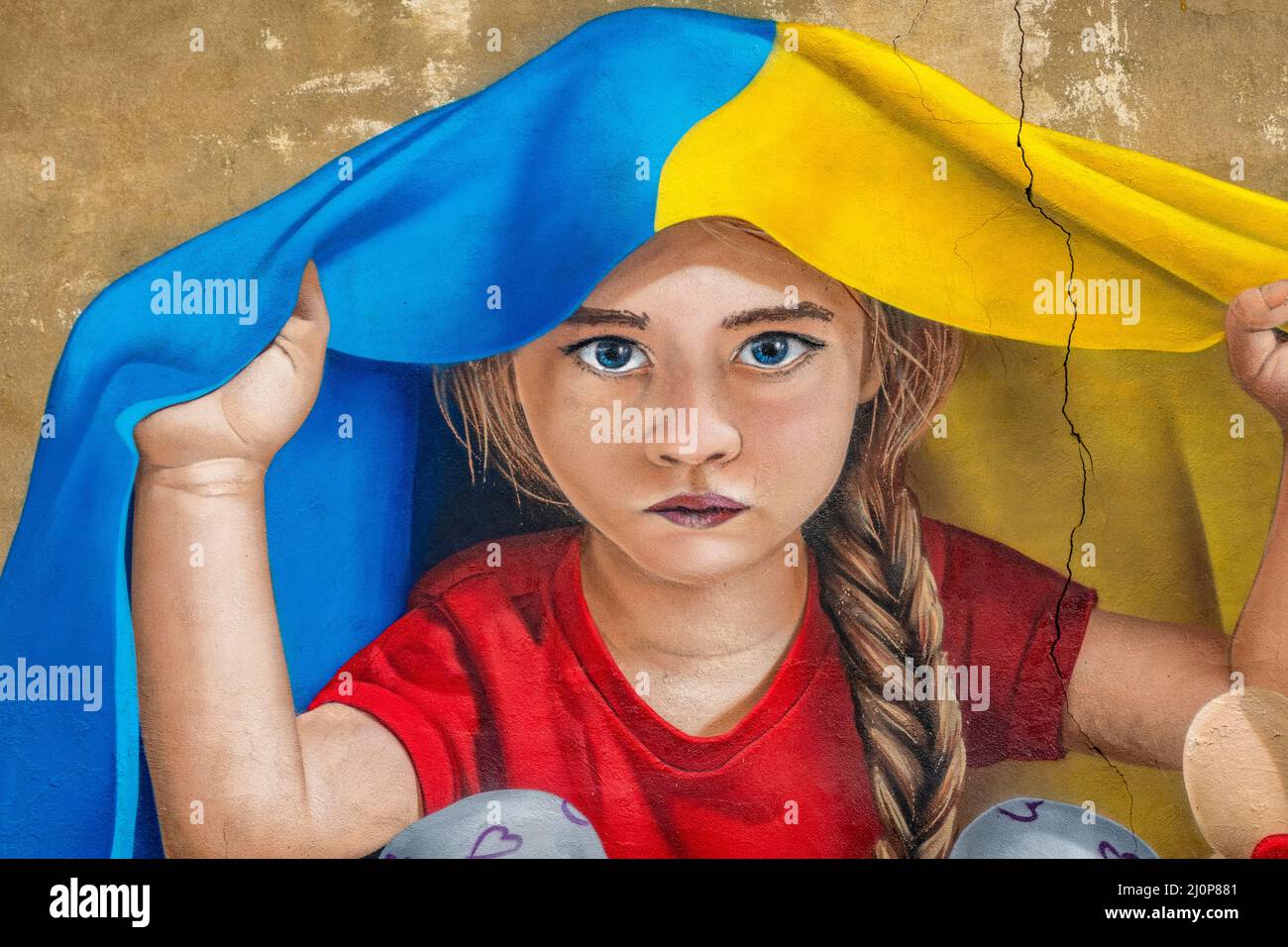 A girl taking shelter under a Ukrainian flag, mural art by ChemiS ...