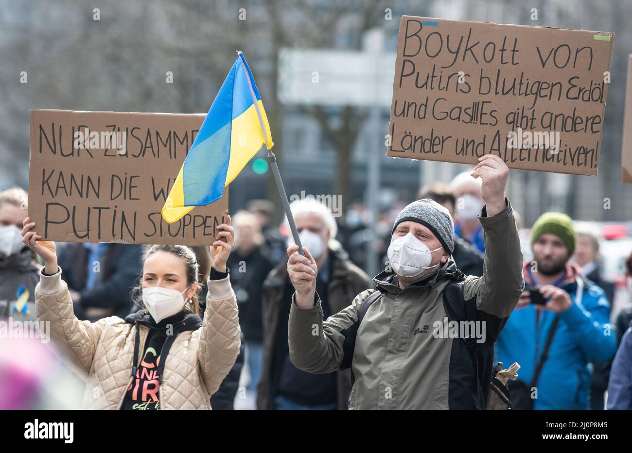 Frankfurt, Germany. 20th Mar 2022. 20 March 2022, Hessen, Frankfurt/Main: Participants in a demonstration on Goetheplatz against the war in Ukraine hold placards reading 'Only together can the world stop Putin' (l) and 'Boycott Putin's bloody oil and gas.' Photo: Boris Roessler/dpa Credit: dpa picture alliance/Alamy Live News Stock Photo