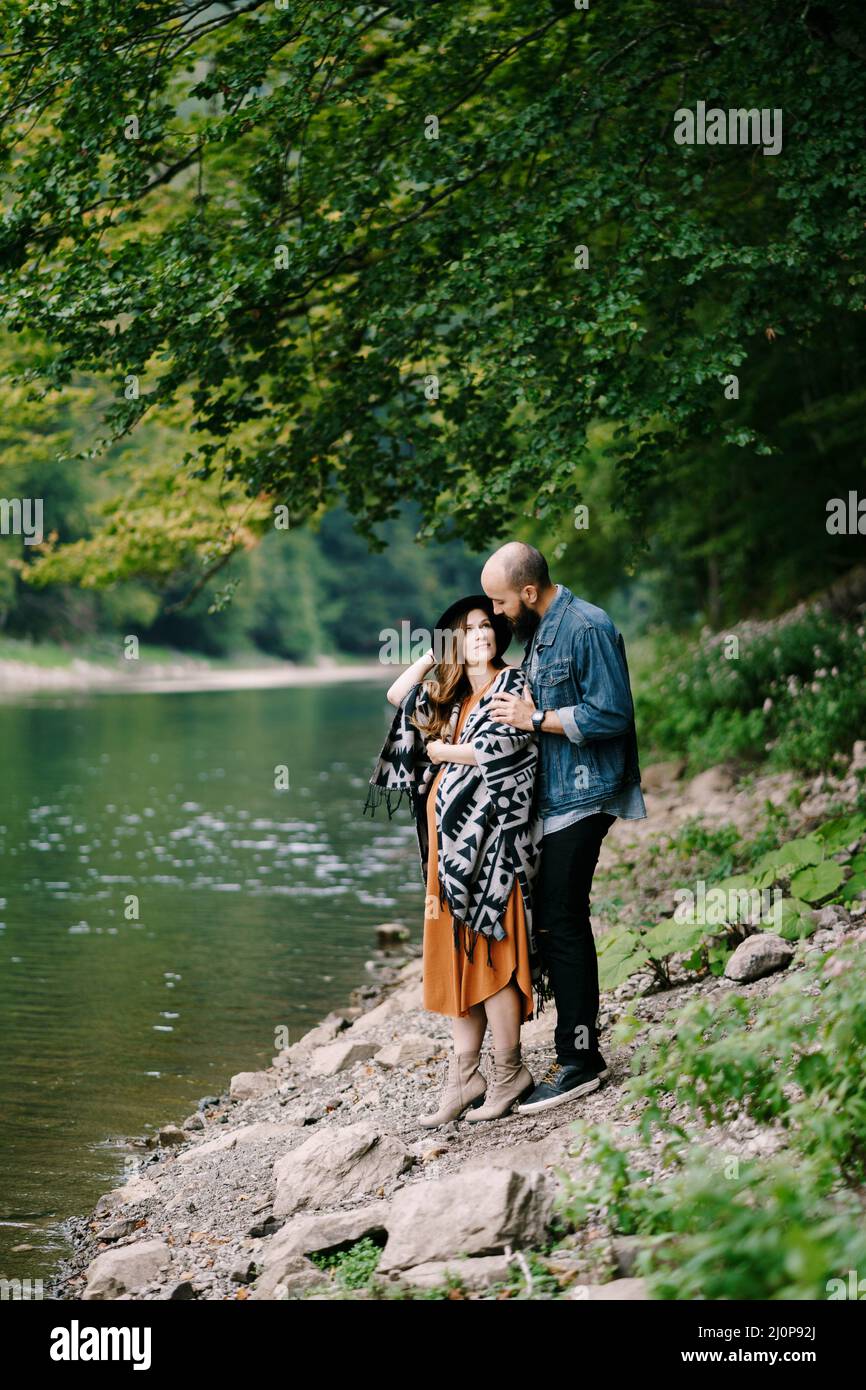 Man hugs the shoulders of a pregnant woman by the lake Stock Photo - Alamy