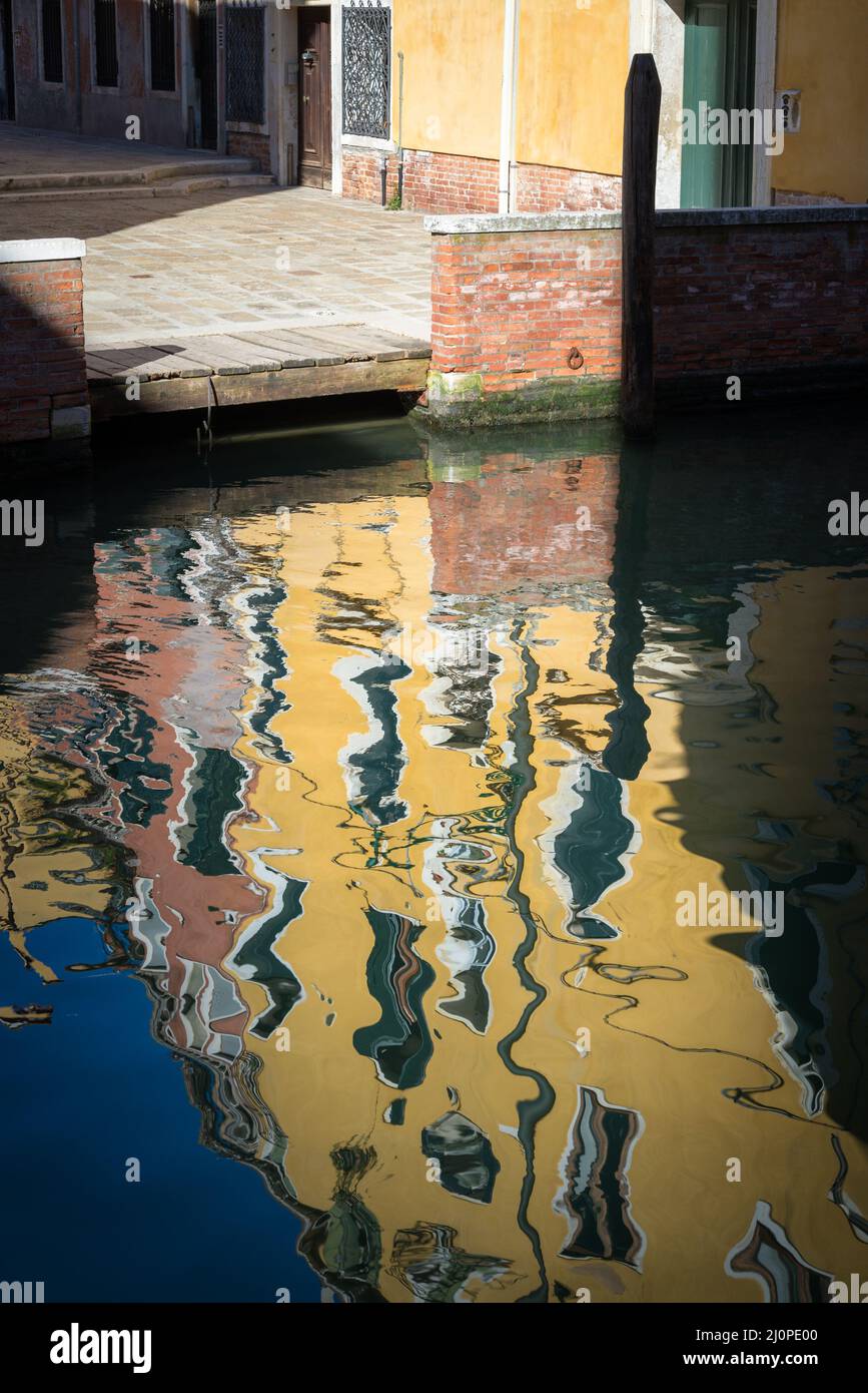 Boats docking, laundry, balcony with plant in a small old colorful street in Venice, Italy Stock Photo