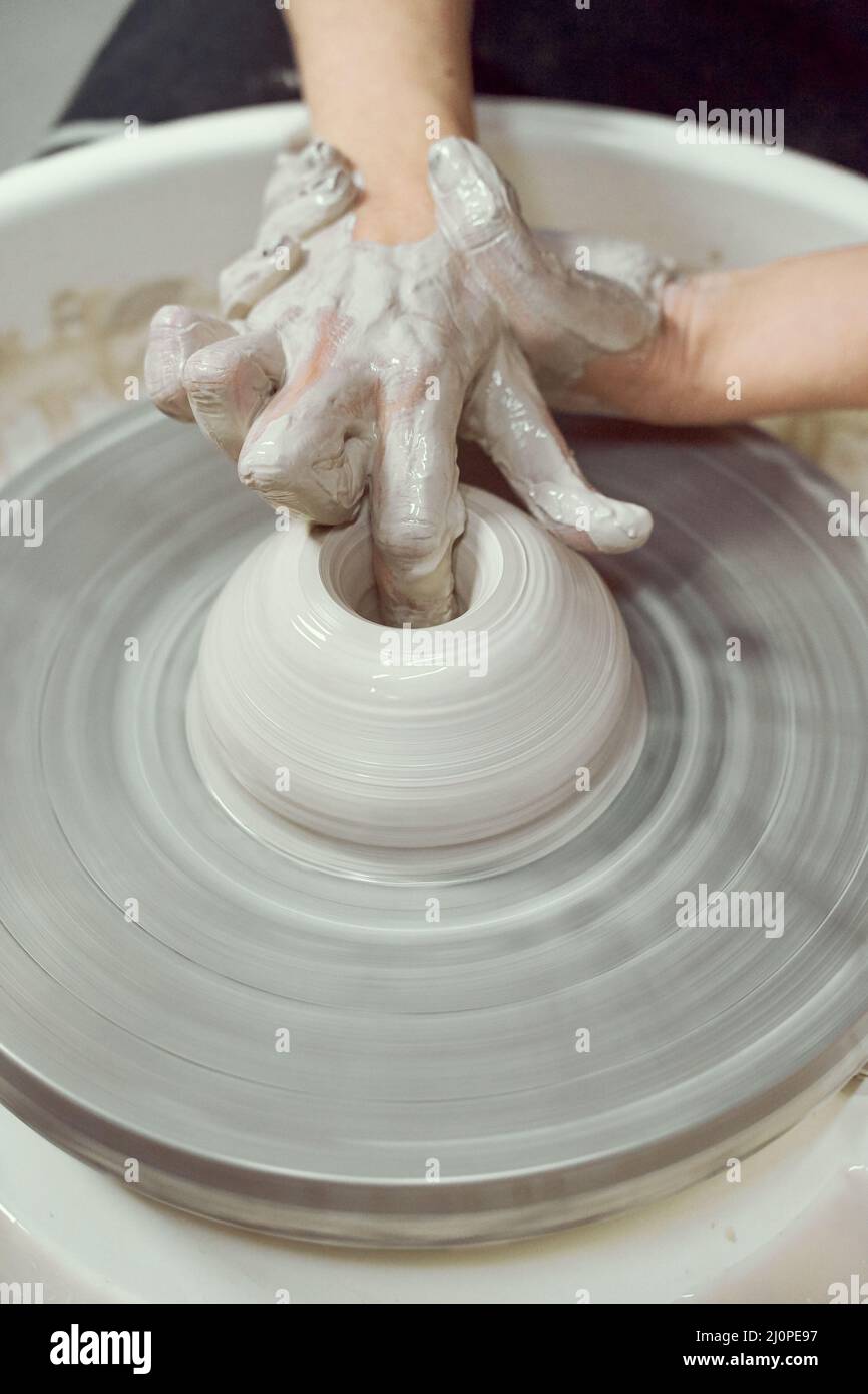 Woman making ceramic pottery, four hands closeup, focus on potters