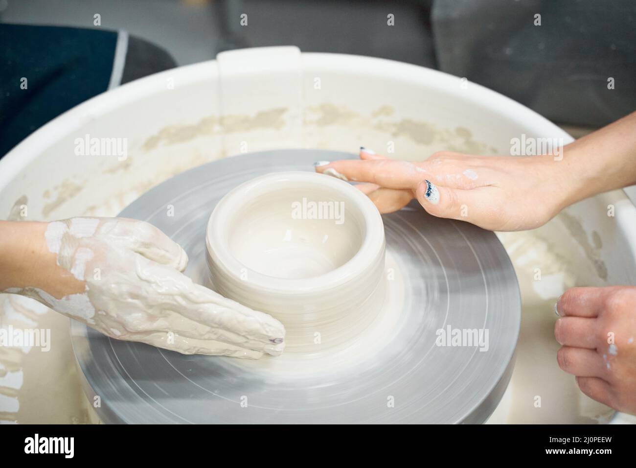 Woman making ceramic pottery, four hands closeup, focus on potters