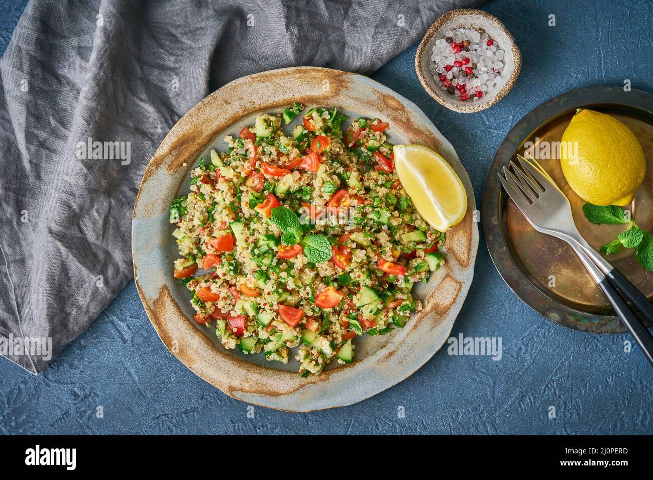 Tabbouleh salad with quinoa. Eastern food with vegetables mix on dark table, vegan diet. Top view Stock Photo