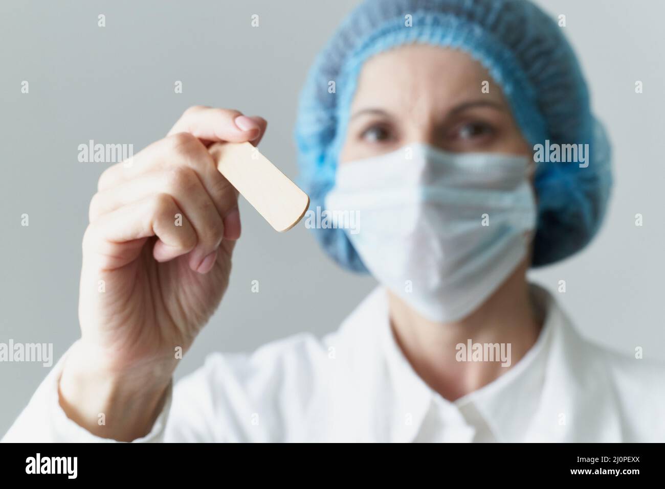 Female doctor in medical mask and uniform check up condition of throat. Illness protection, Stock Photo