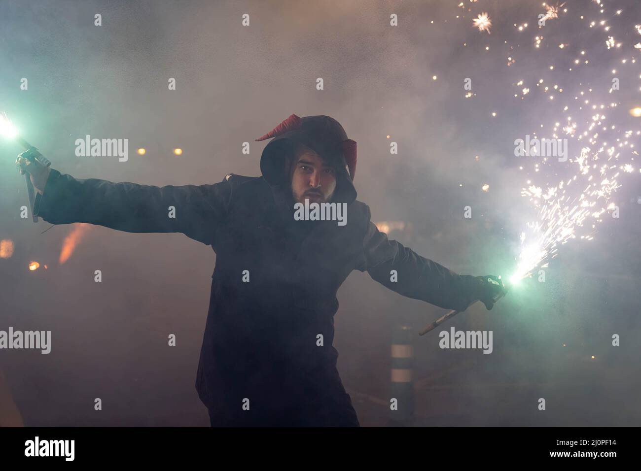 A hooded man runs while holding fireworks in his hand during the Parade ...