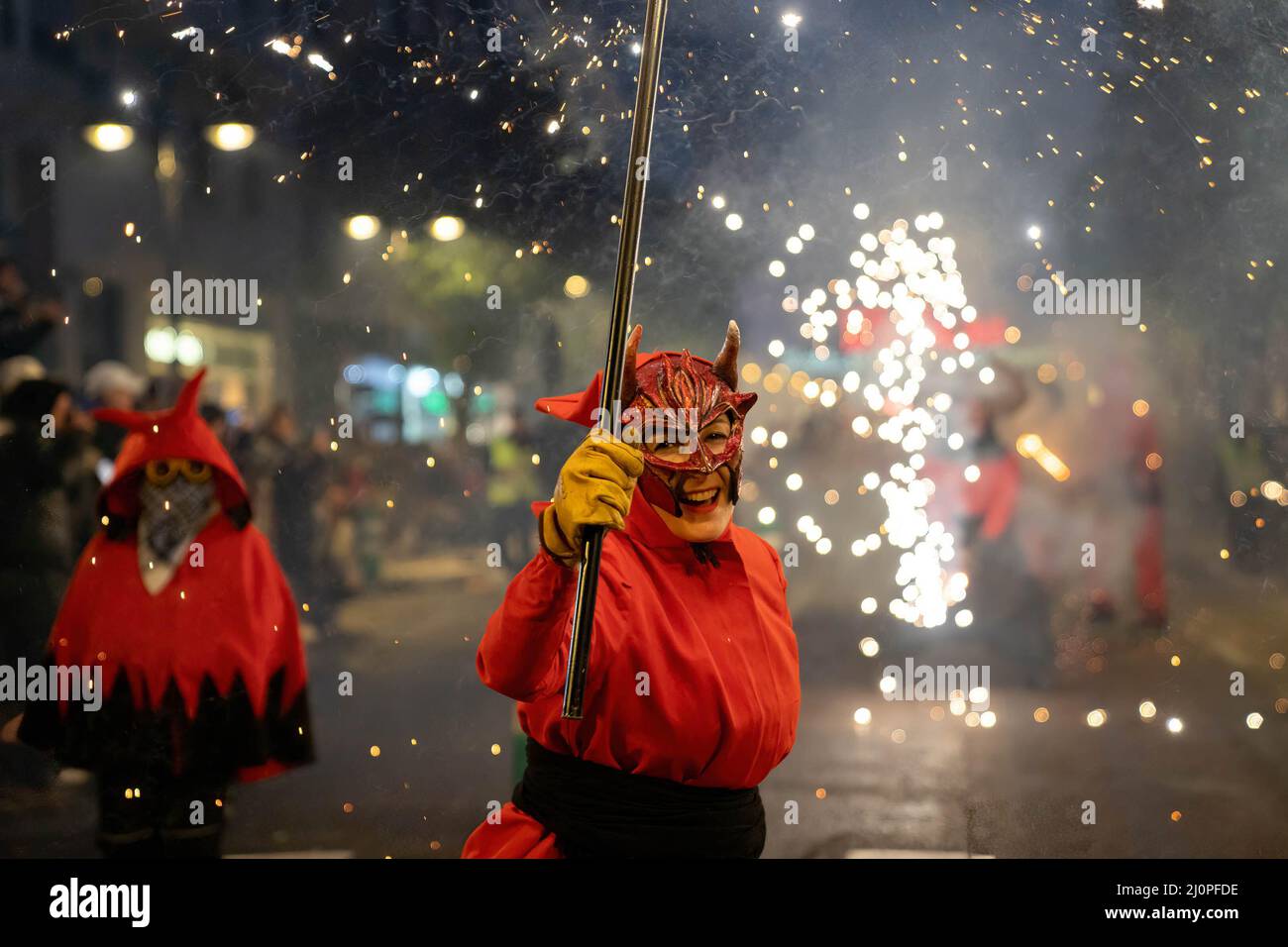 A woman dressed as a demon holds firecrackers during the Parade of Fire ...