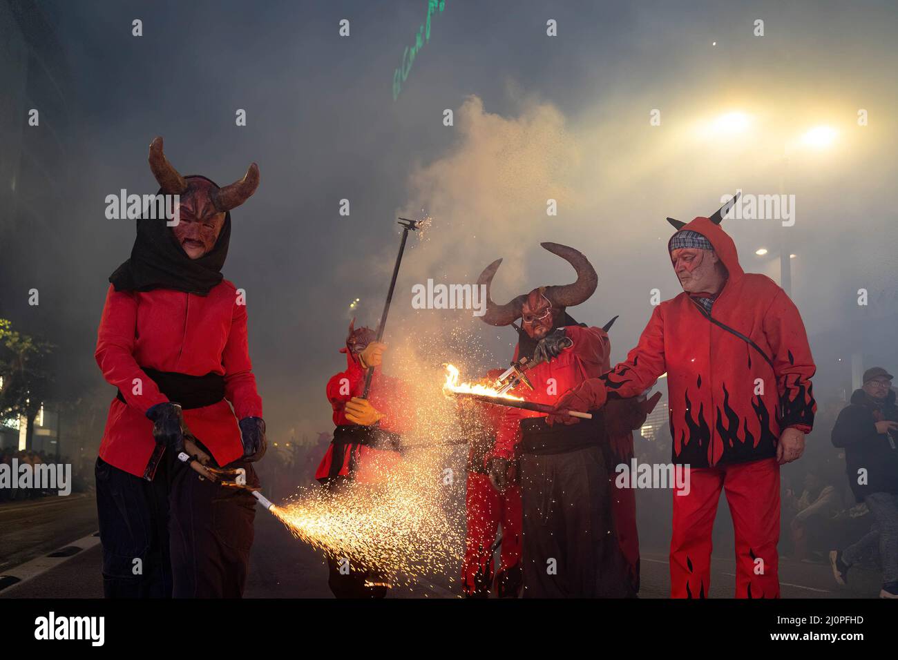 Several people dressed as demons light firecrackers during the Parade ...