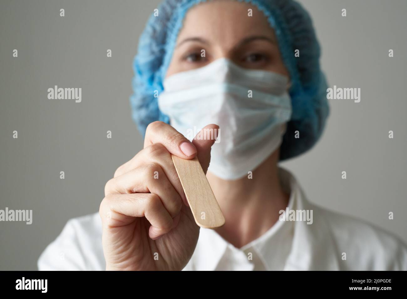 Female doctor in medical mask and uniform check up condition of throat. Illness protection, Stock Photo