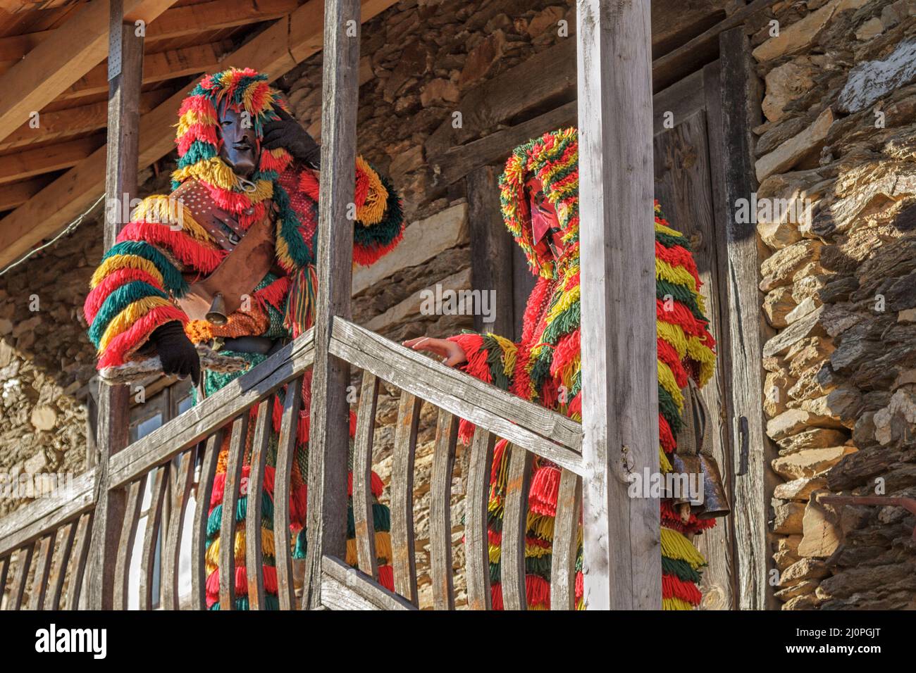 Two Caretos by a traditional schist house, Podence. Portugal Carnival Stock Photo