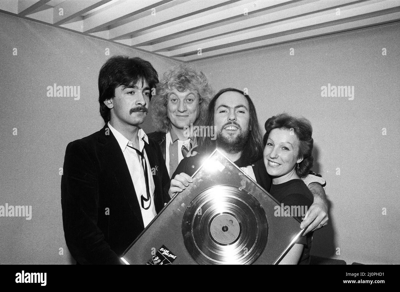 Midland pop stars Slade raised £385 when they appeared on Central TV's Saturday Starship and auctioned a gold disc copy of Slade's Smash Hits, in aid of the Ethiopian famine appeal. Slade's Dave Hill and Noddy Holder are pictured with fan Frances Tucker from Rushden. 1st December 1984. Stock Photo