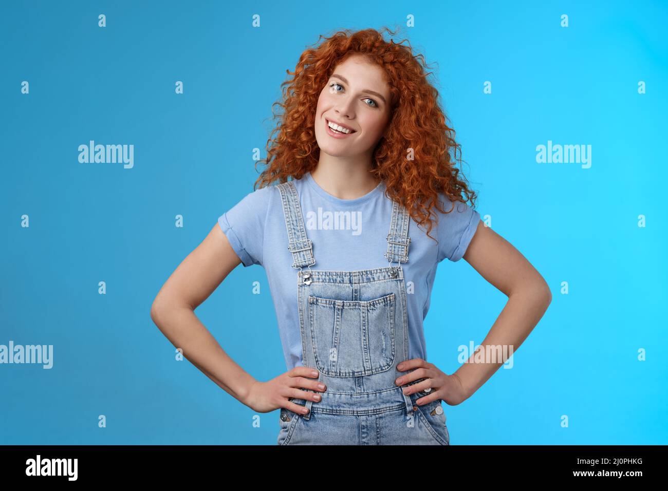Cheerful motivated accomplished attractive redhead curly-haired ginger girl hold hands waist confident pose assertive own power Stock Photo