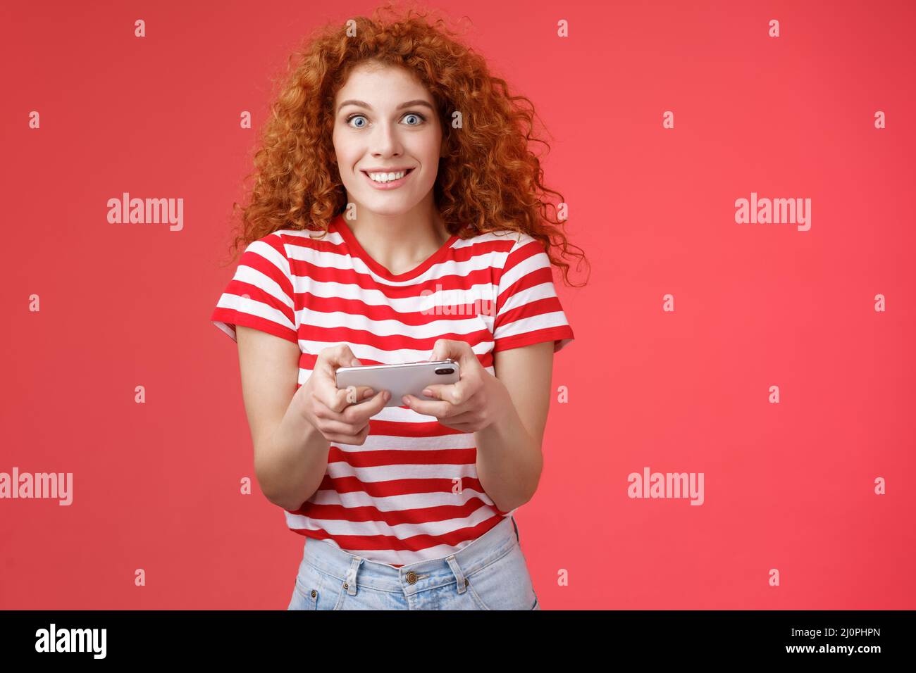 Excited happy cute redhead curly-haired girlfriend eager start learn how play boyfriend game look amused cheerful camera smiling Stock Photo