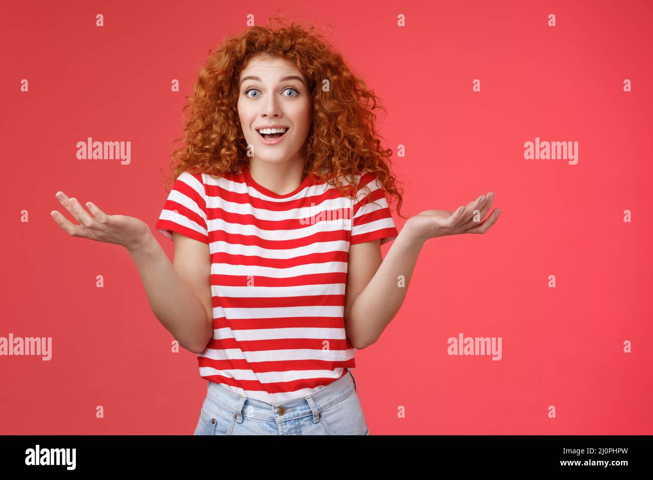 Unaware carefree clueless attractive redhead woman curly hairstyle shrugging unaware hands spread sideways smiling uncertain ask Stock Photo