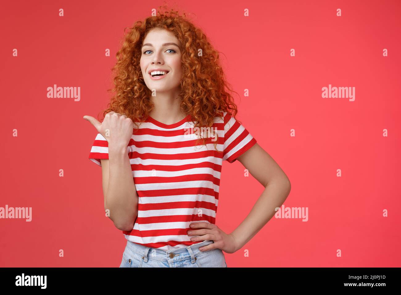 Accomplished good-looking redhead curly woman raise head proudly confident pointing thumb left smiling camera assertive sharing Stock Photo