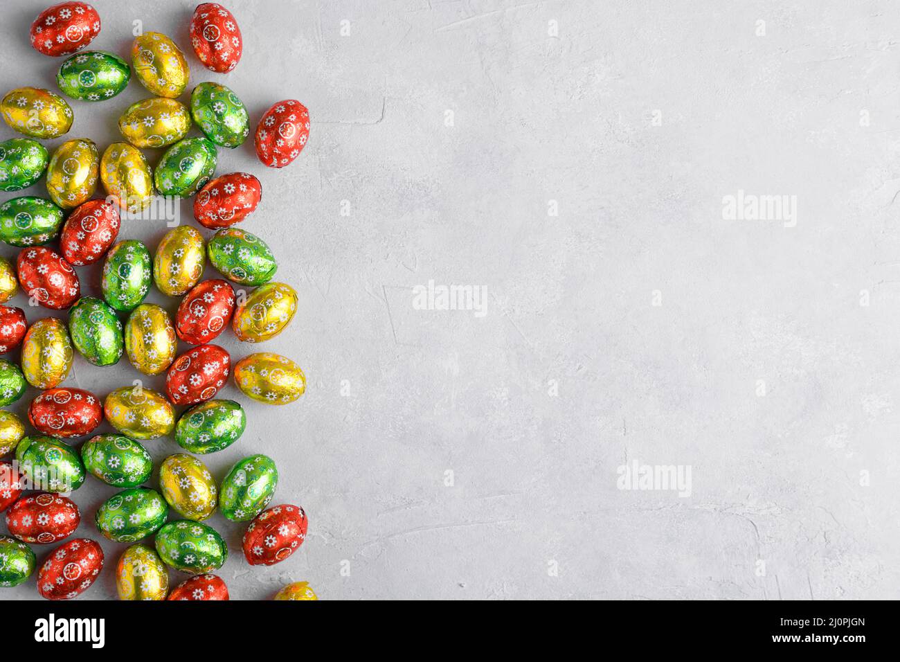 Colorful Easter eggs on a grey background with space for text, top view, flat lay. Easter festive background Stock Photo
