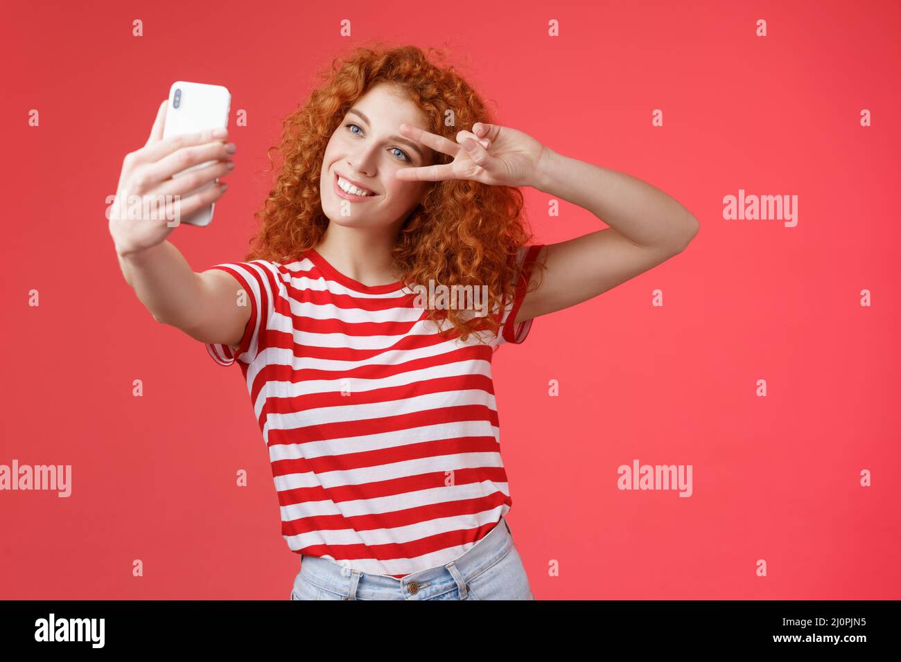 Hey followers how your summer holidays. Cheerful self-assured stylish fashionable redhead curly girl strike pose show peace vict Stock Photo