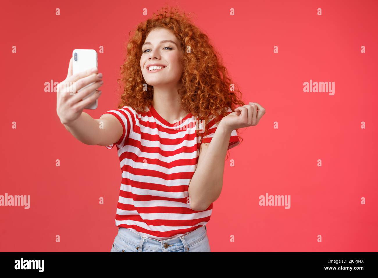 Cute pleased happy good-looking redhead ginger girl curly hairstyle smiling perfect toothy grin posing delighted amused hold sma Stock Photo