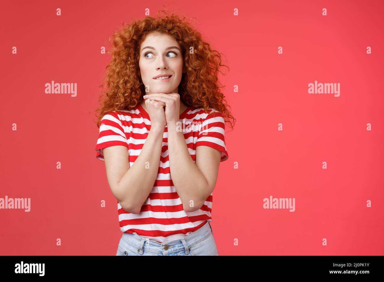 Cheerful intrigued redhead silly curly-haired woman smiling interested hold hands chin face-line imaging thinking about tasty bu Stock Photo