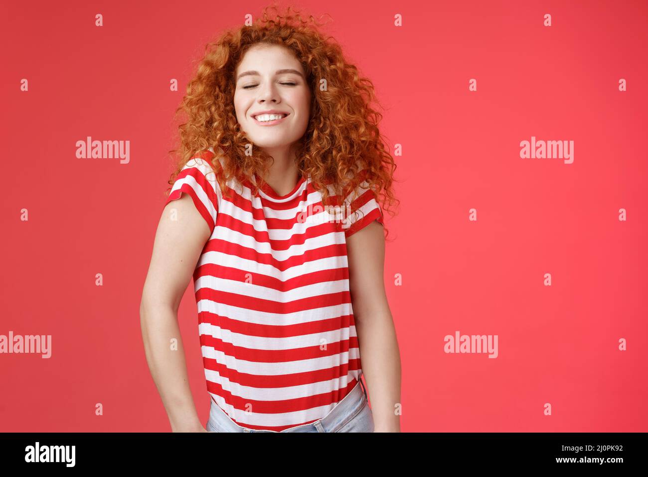 Cheerful relaxed carefree happy attractive redhead curly woman close eyes enjoy sunlight warm summer holiday weekends smiling br Stock Photo