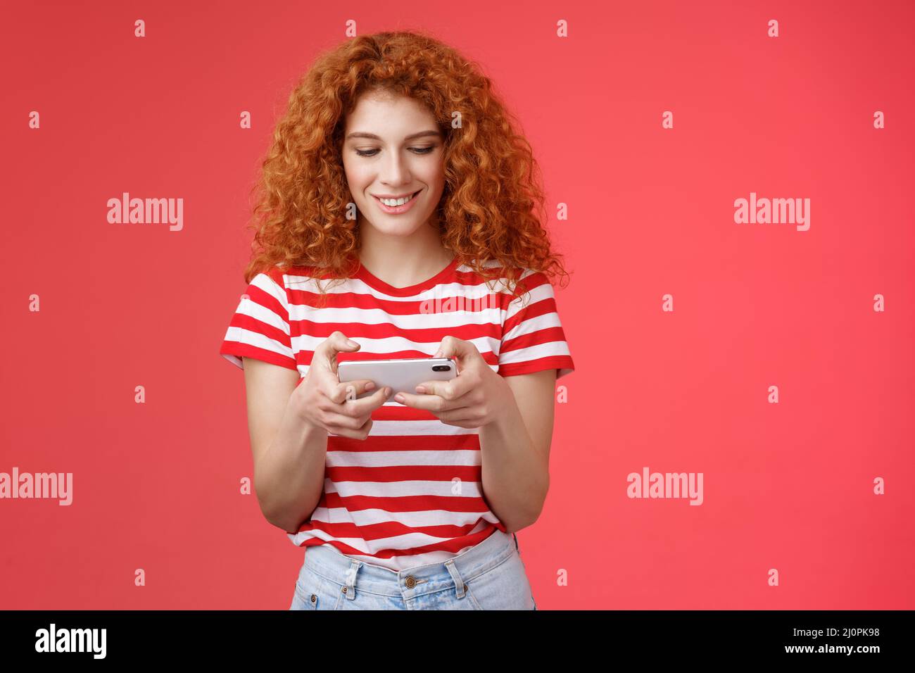 Redhead girl fool around waiting queue dentist playing awesome smartphone game hold phone horizontal tap cellphone screen look t Stock Photo