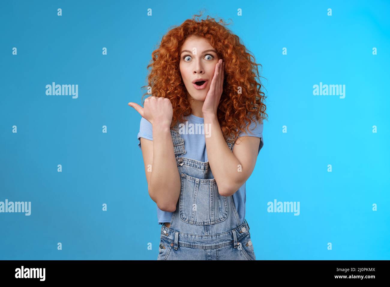 Omg how intriguing. Impressed charismatic emotive surprised redhead cute curly girl open mouth gasping curious amazed touch chee Stock Photo