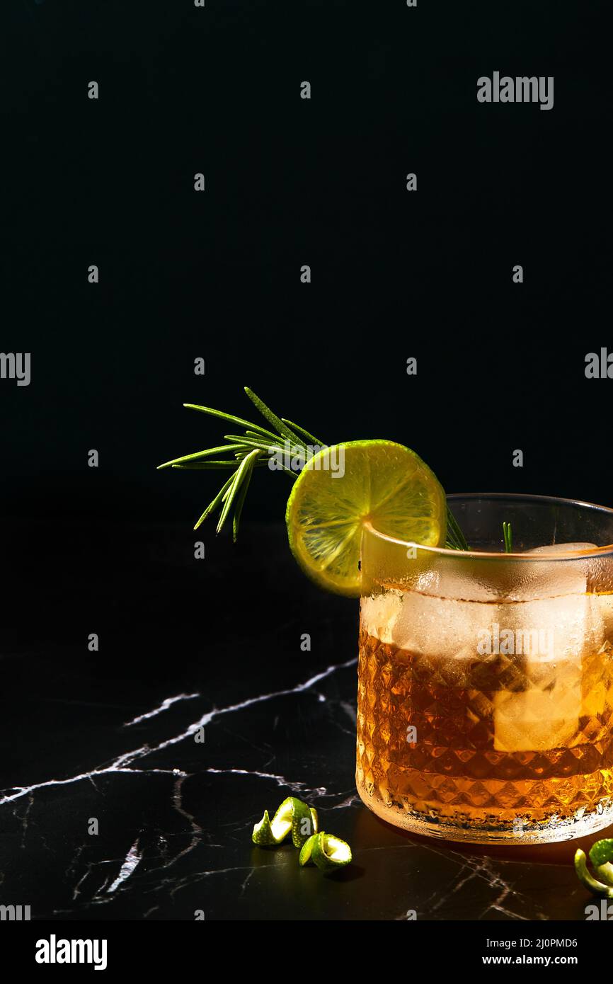 Alcoholic or non-alcoholic cocktail with lime and rosemary on a dark marble table Stock Photo