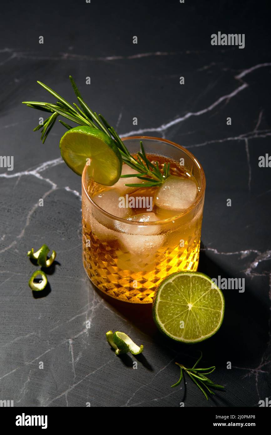 Alcoholic or non-alcoholic cocktail with lime and rosemary on a dark marble table Stock Photo