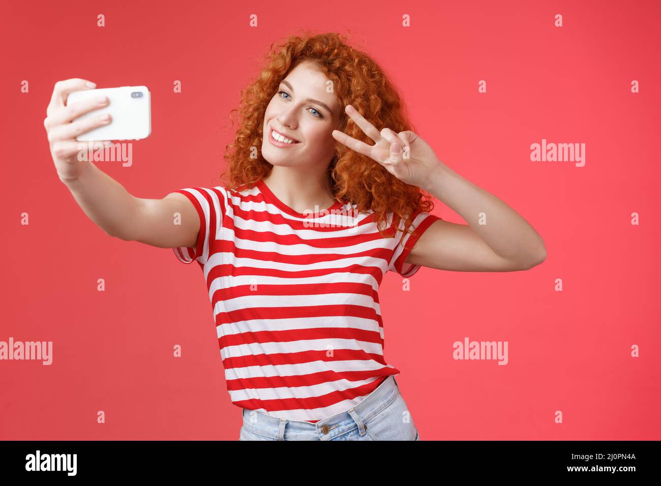 Stylish carefree good-looking redhead curly woman enjoy summer holidays show victory peace gesture eye tilt head cute record vid Stock Photo