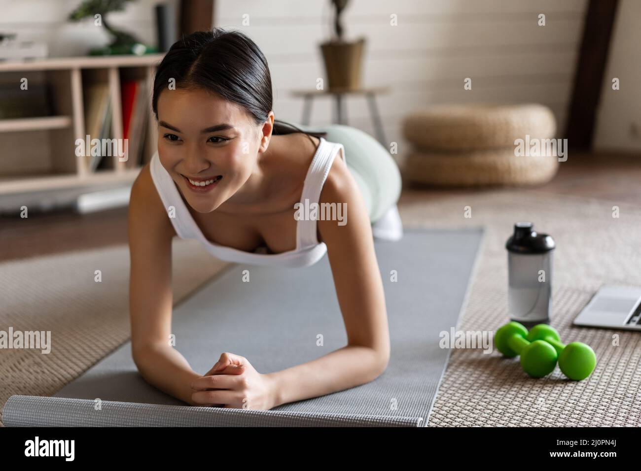 Sporty asian girl in activewear doing workout at home, follow video sport guide, online fitness instructor on laptop, standing i Stock Photo