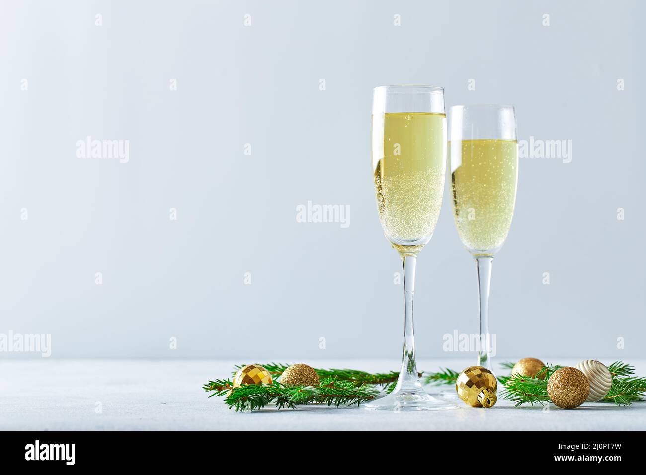 Glasses with sparkling wine type champagne with fir branches and golden