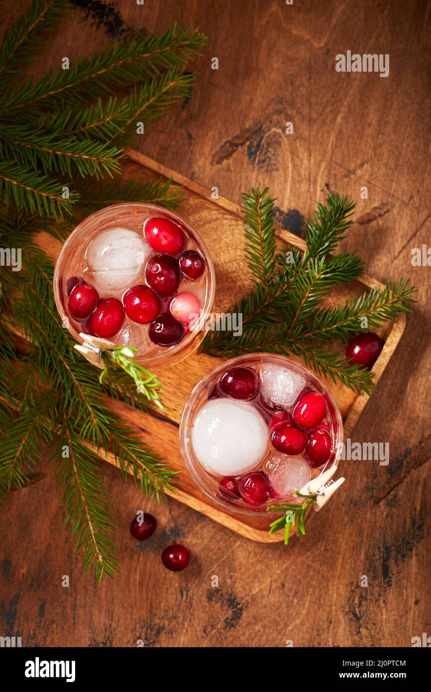 Alcoholic cocktail or non-alcoholic cocktail with vodka and cranberries with ice with fir branches on wooden background Stock Photo