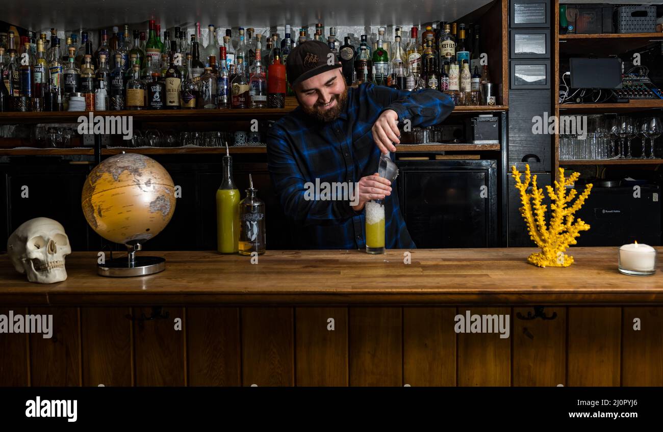 Male bartender making fruit cocktail in bar, Edinburgh, Scotland, UK Stock Photo