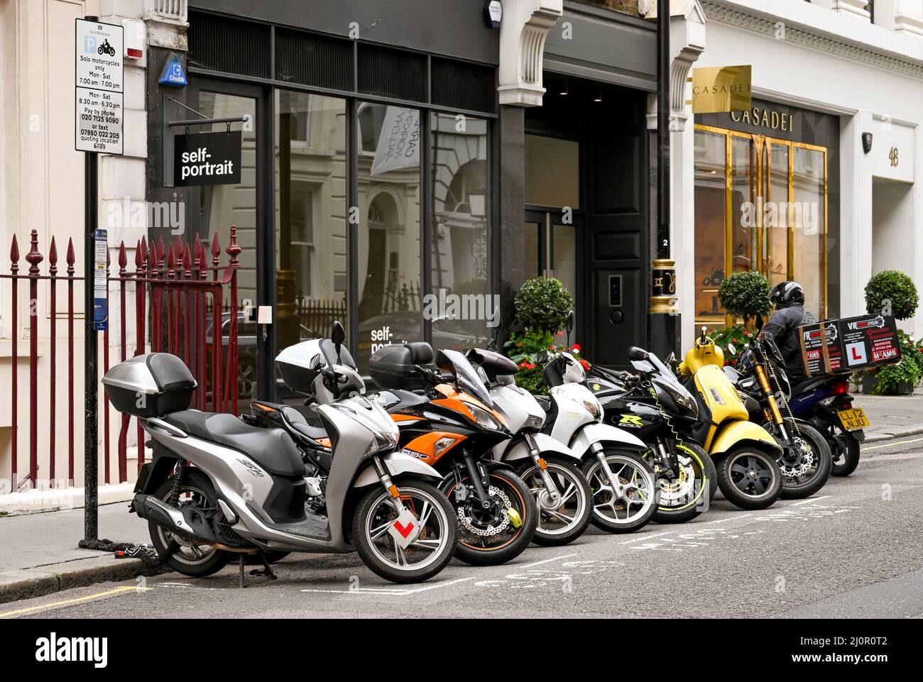 London, England - August 2021: Row of scooters parked in a designated parking bay on a London street Stock Photo