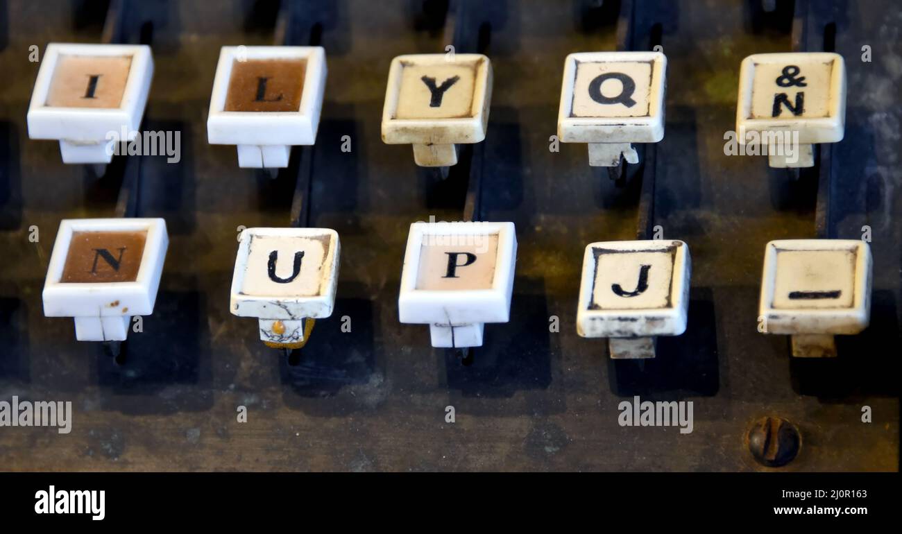 Well worn keys of Linotype Machine line bottom of image.  Letters are worn and metal is aged. Stock Photo