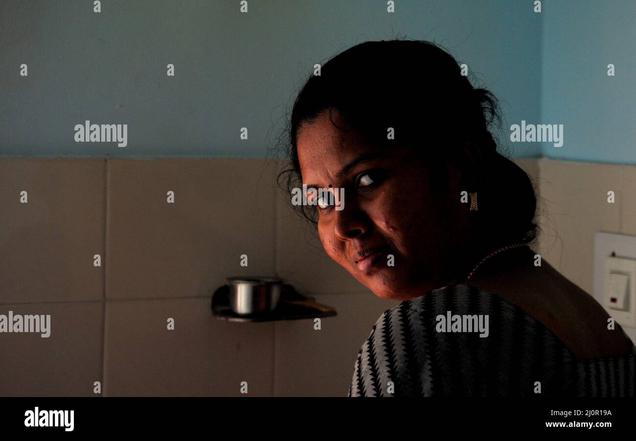 Indian house wife looking at the camera when working in kitchen in an evening Stock Photo