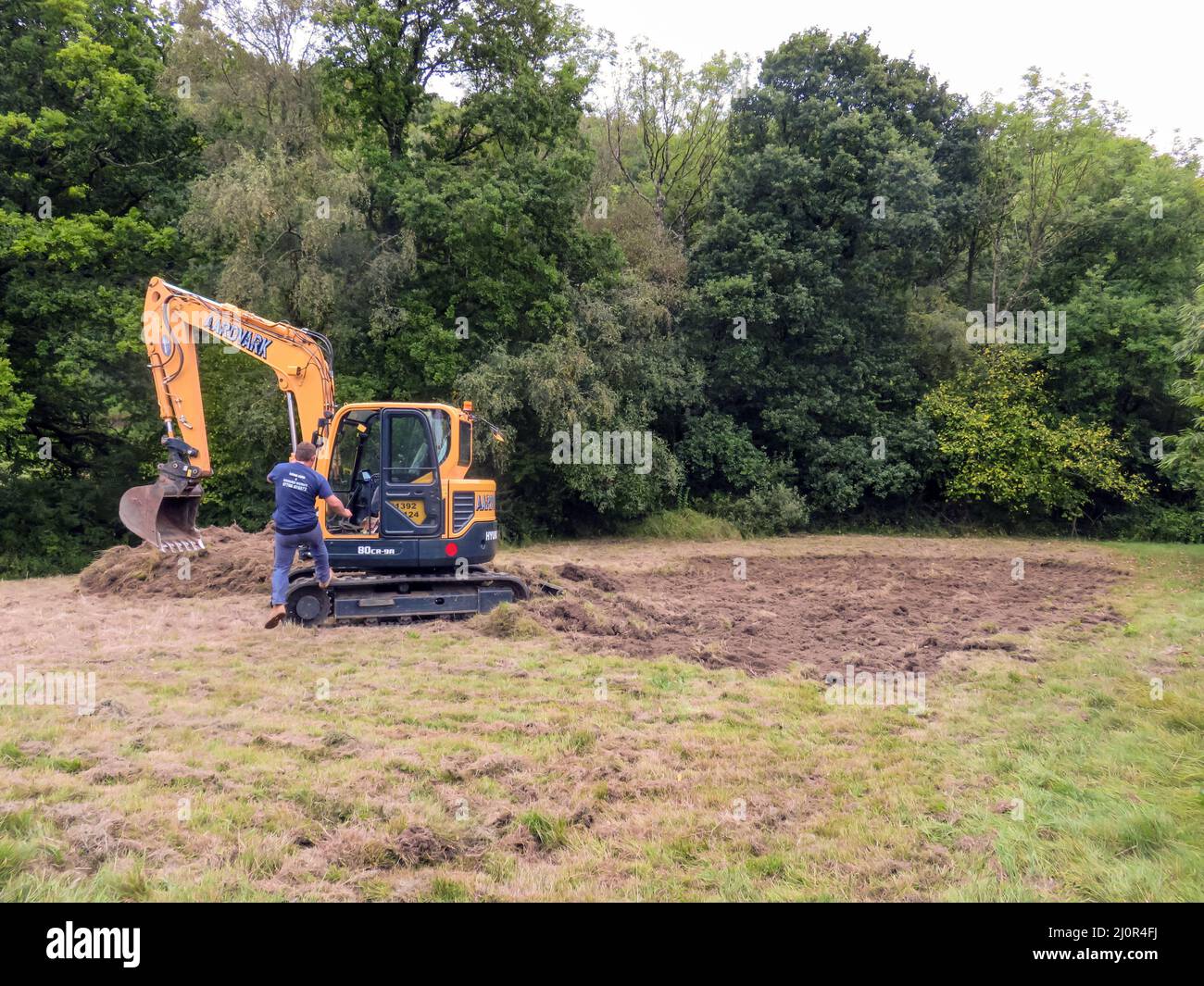 UK, England. Pond construction on a sloping field. 10 x 5 meters. Stage 1. Shaping the area and removing the turf. Stock Photo