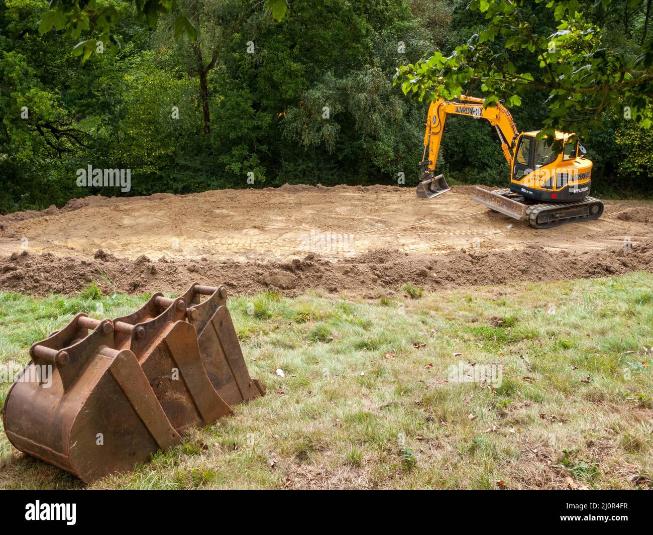 UK, England. Pond construction on a sloping field.10 x 5 meters. Stage two -  shaping, adding to bund below. Stock Photo