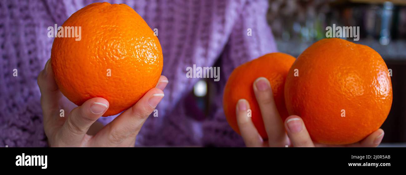Closeup photo of woman holding orange fruit in hand. Healthy eating concept. Stock Photo