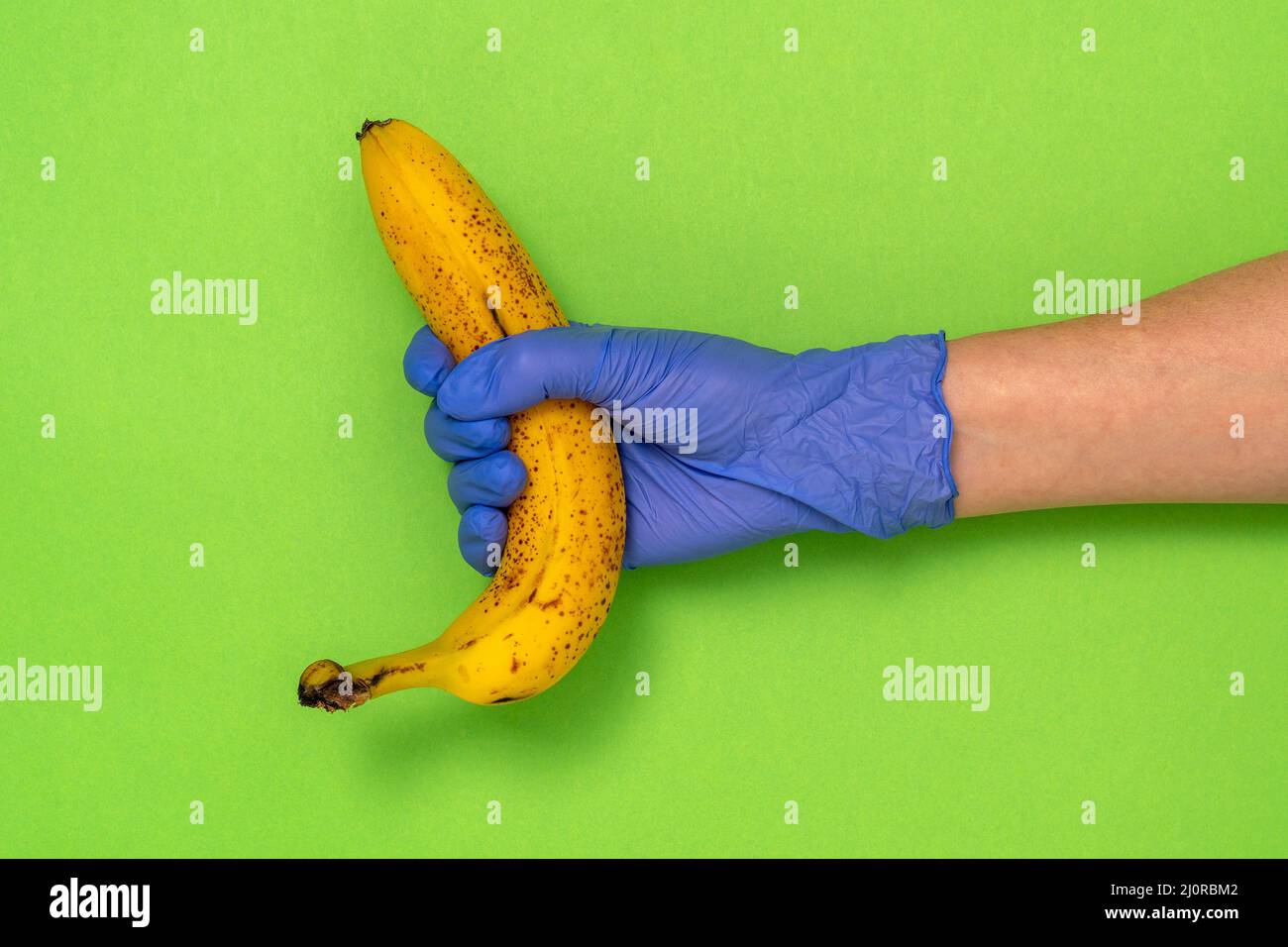 Hand in a latex glove holding a banana Stock Photo Alamy