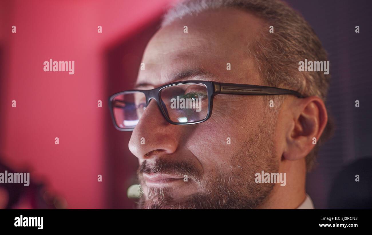 Extreme close-up of bearded middle-aged office worker with glasses. Tired employee of working overtime at night. Stock Photo