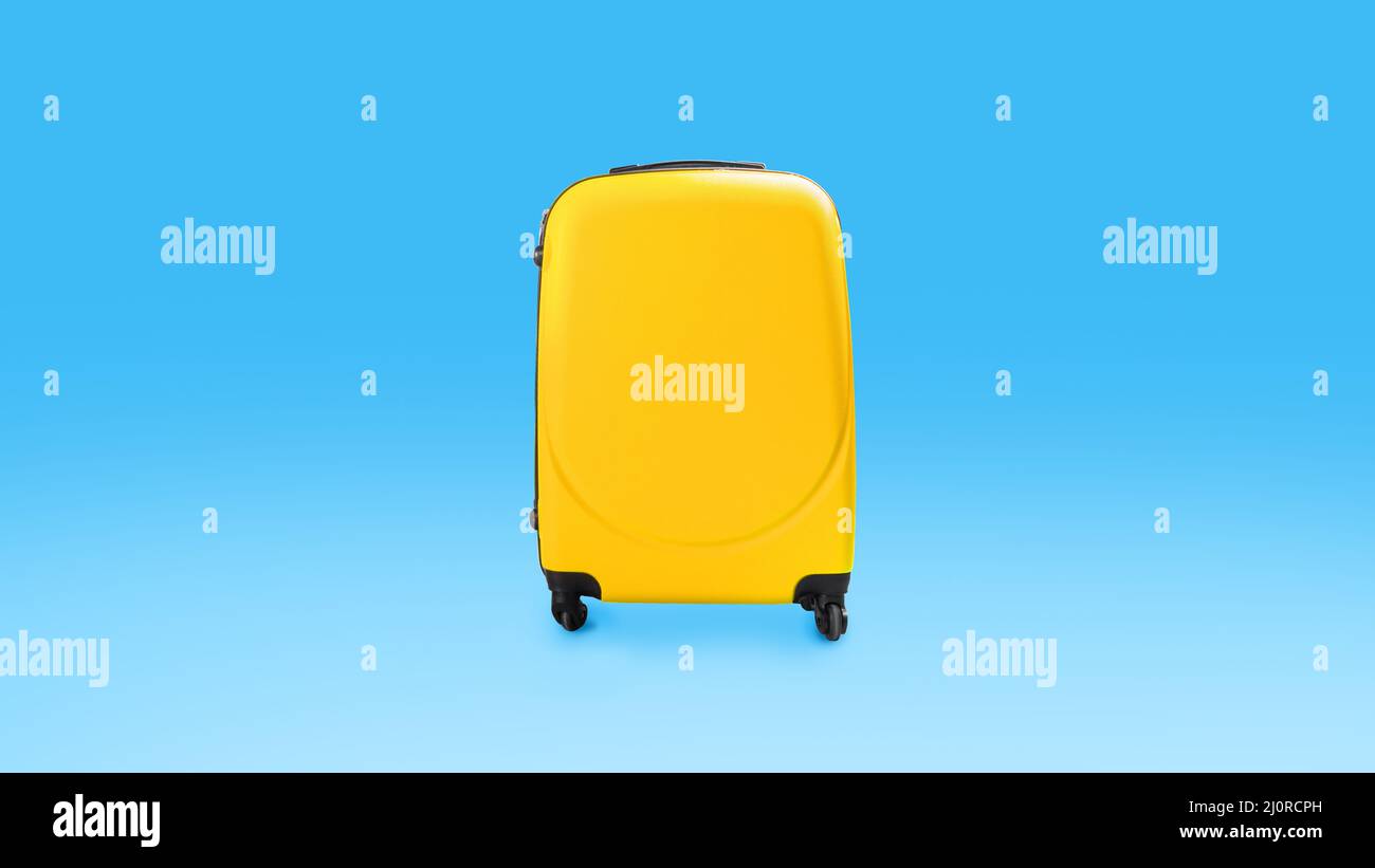 Yellow stylish suitcase isolated over blue studio background wall Stock Photo