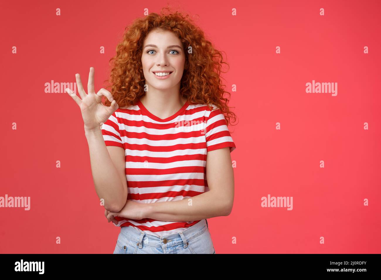 Excellent choice good. Attractive cheerful european redhead curly woman show okay ok approval gesture smiling toothy delighted s Stock Photo