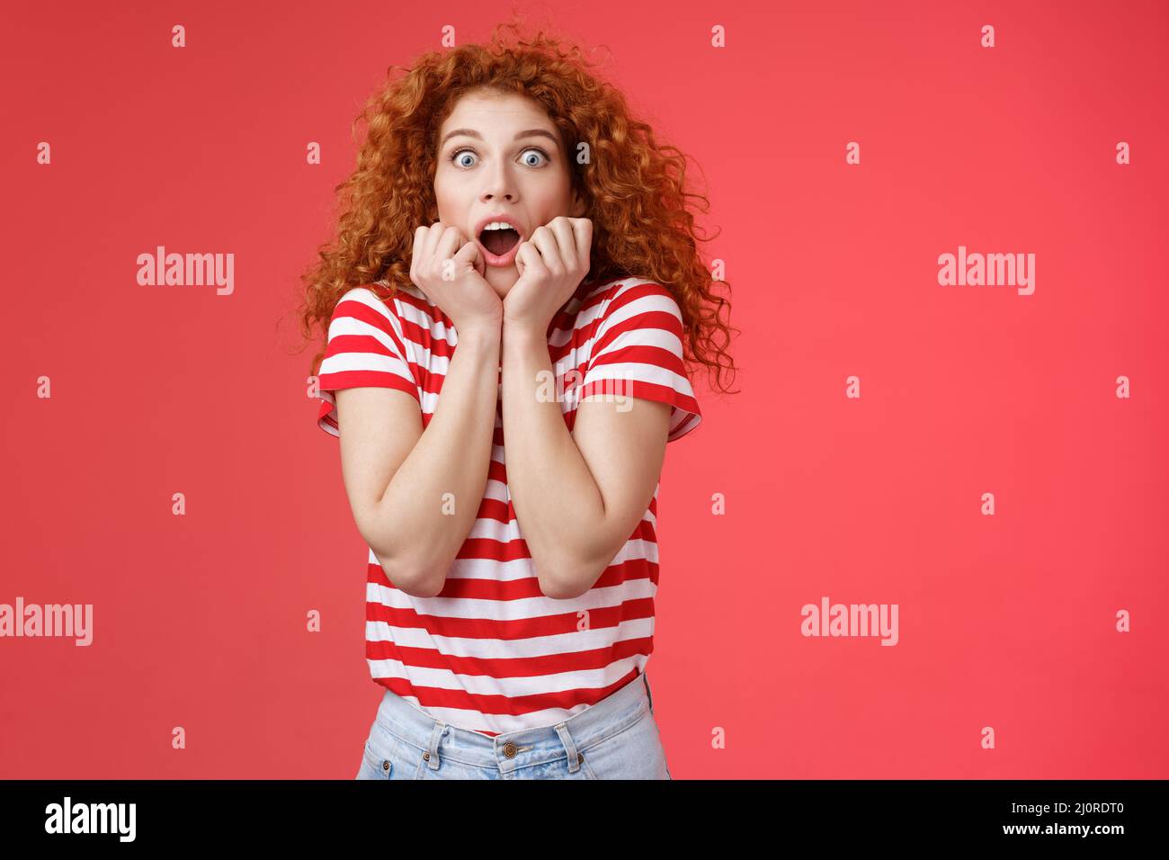 Shocked scared ambushed redhead curly-haired cute girlfriend insecure gasping drop jaw scream frightened stare camera hold hands Stock Photo