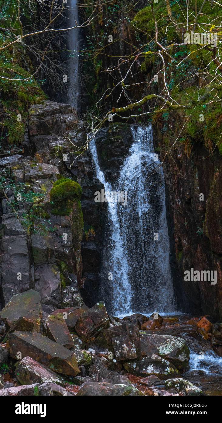 Vertical shot of a small waterfall in the middle of a rocky place in ...