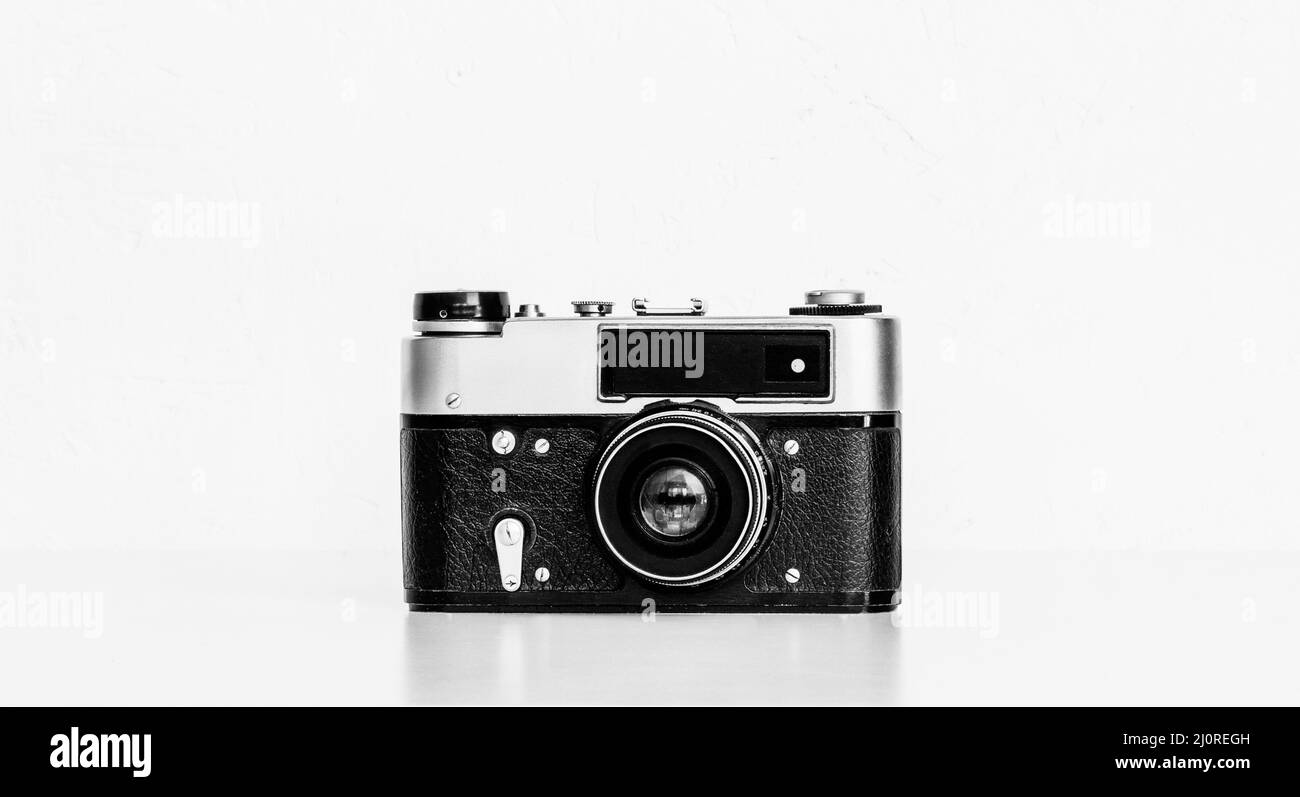 Vintage film camera on a table against a white wall close-up black and white photo Stock Photo
