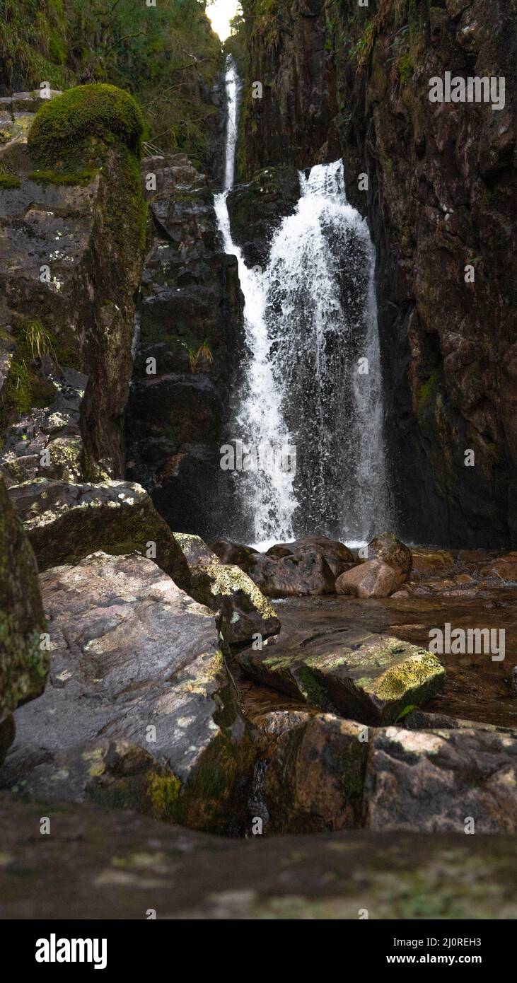 Vertical shot of a small waterfall in the middle of a rocky place in ...
