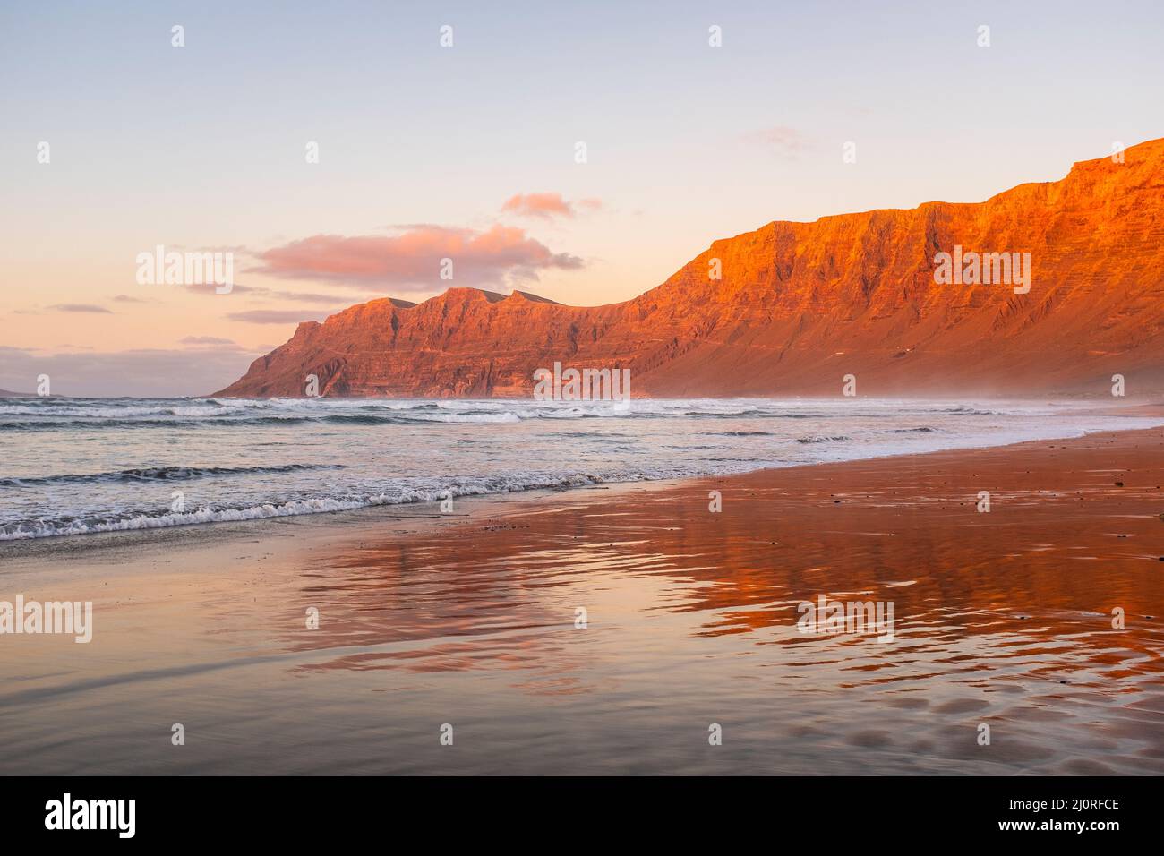 View of amazing beach during red sunset time. Ocean water and shore. Mountains in background with clear sky. Summer holiday vacationand scenic beautif Stock Photo