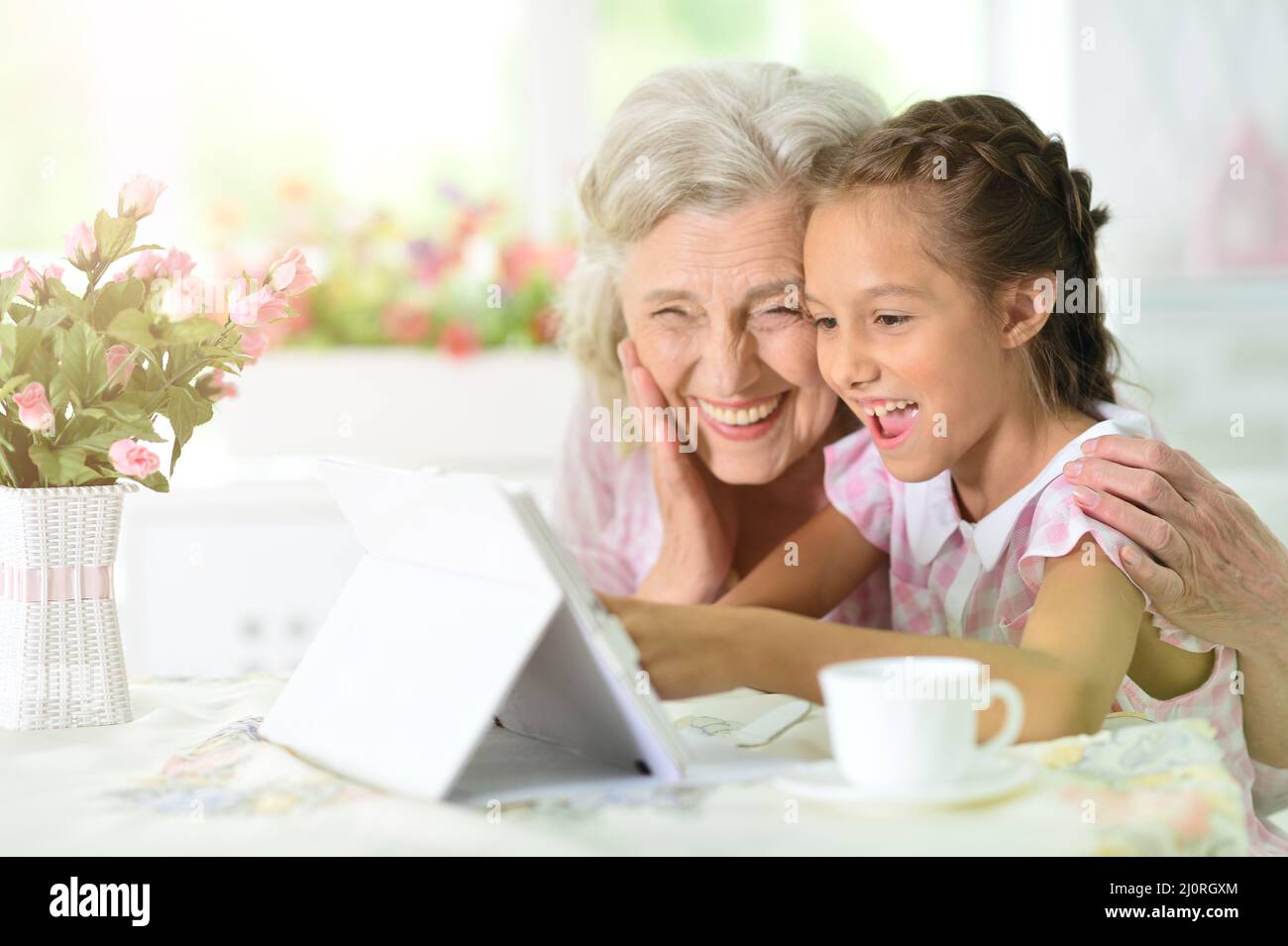Cute little girl with her grandmother with tablet Stock Photo - Alamy