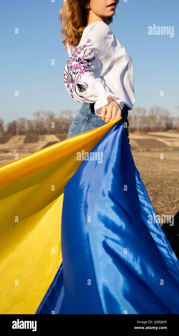 unrecognizable woman wearing traditional embroidered shirt with yellow blue Ukrainian flag. request for help to Ukraine, drawing attention to support Stock Photo